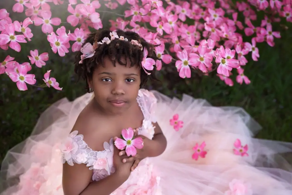 Girl in soft pink gown surrounded by blooming dogwood flowers.