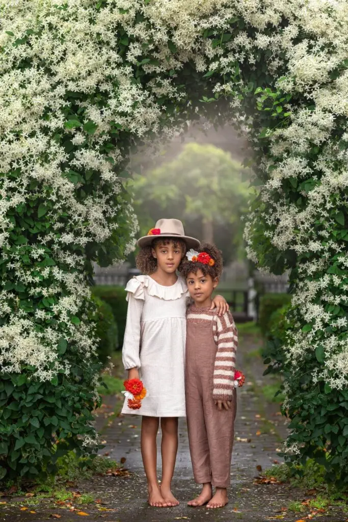 Cincinnati photographer capturing child under floral arch with soft greenery and white blooms