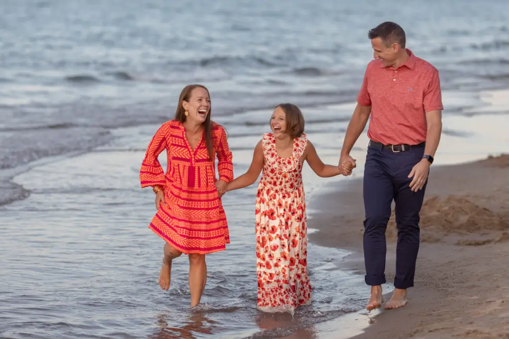 family photography session on the beach with parents and children walking together at sunset