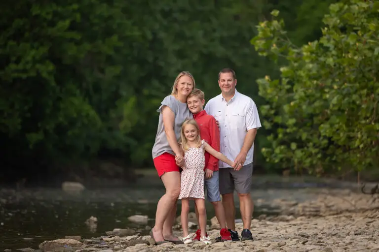 Cincinnati family photographer capturing family of four standing together by river outdoors